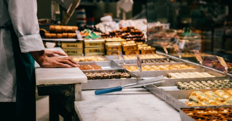 Tongs - Crop anonymous male seller at counter with assorted traditional Turkish sweets in market