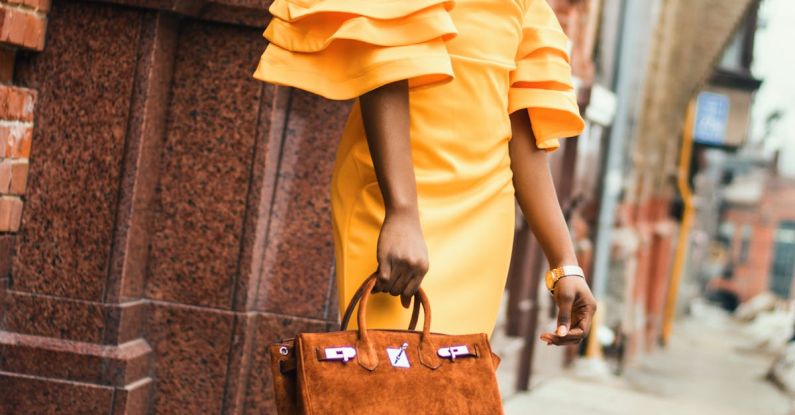 Metals - Woman Standing and Holding Brown Handbag