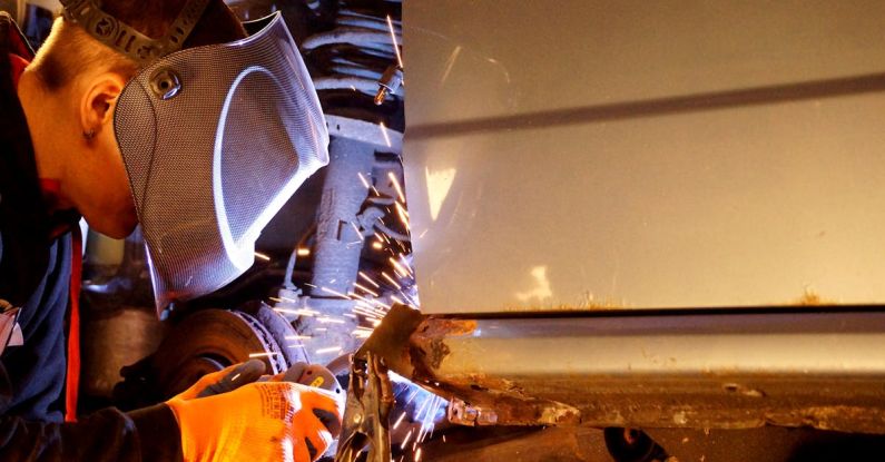 Forge Welding - A man welding on a car in a garage