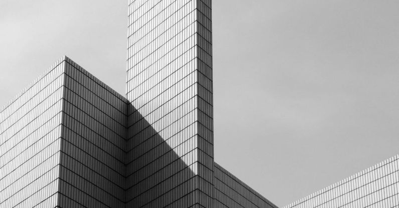 Complex Shapes - From below black and white of contemporary geometric construction exterior with tall walls under light cloudy sky in sunny day