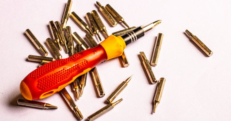 Tool Steel - A red screwdriver and a pile of screws on a white background