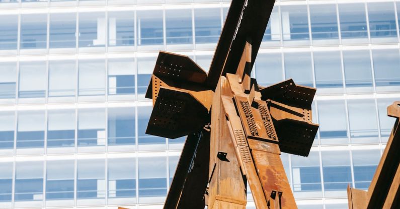 Metal Project - Low angle of rusty metal part of building under construction against office tower in developing district