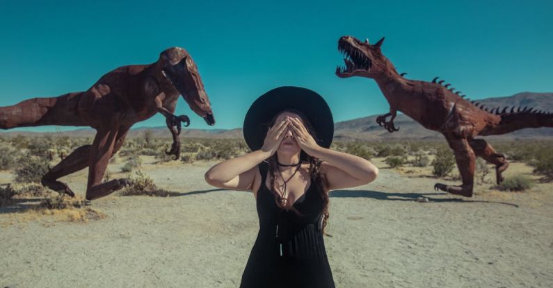 Metal Sculptures - A Woman Covering her Eyes Near the Dinosaur Sculptures in Borrego Springs California