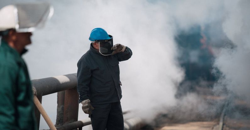Ironwork - Workers in Protective Clothing Standing by Smoke